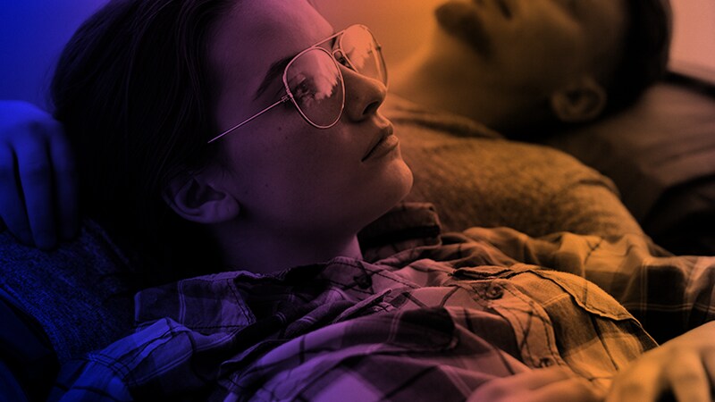 Ung kvinde med briller som ligger i sengen