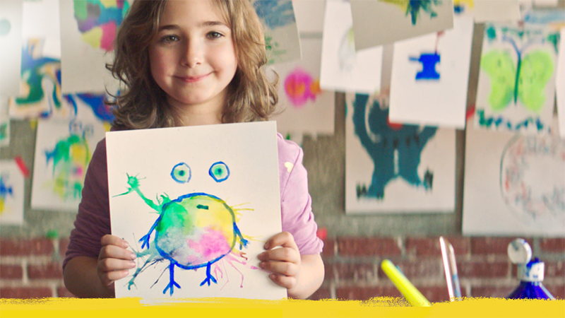 En pige viser sin akvareltegning. Hun har malet et billede af sin tumor